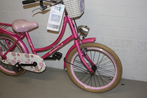 de voorkant van een roze popal kinderfiets met lichtroze mandje/zadel en witte kettingkast